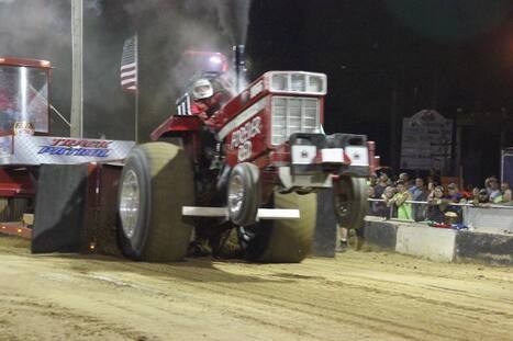 Tractor pulling sled at dusk during Nabor Days