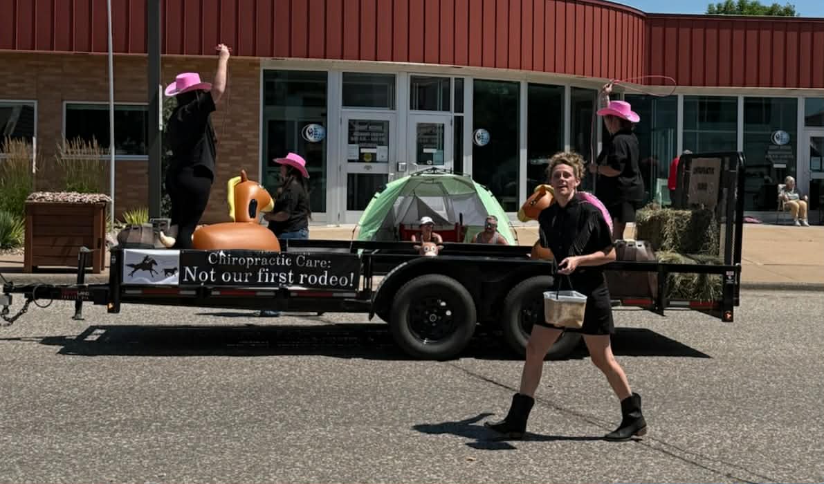 Themed parade float reading 'Chiropractic Care: Not our first rodeo!' rolls down Main Street