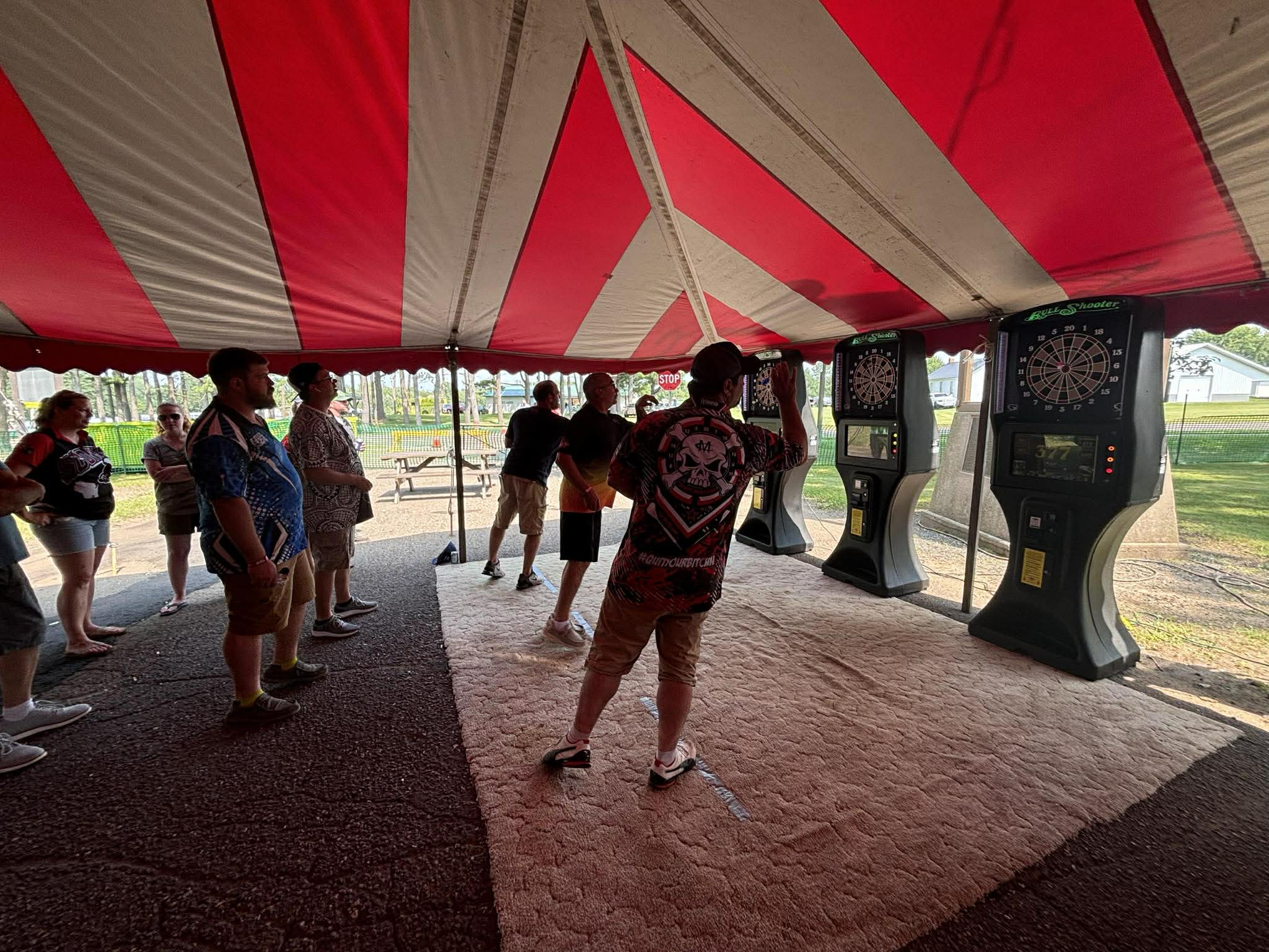 Dart tournament crowd inside the red and white striped tent