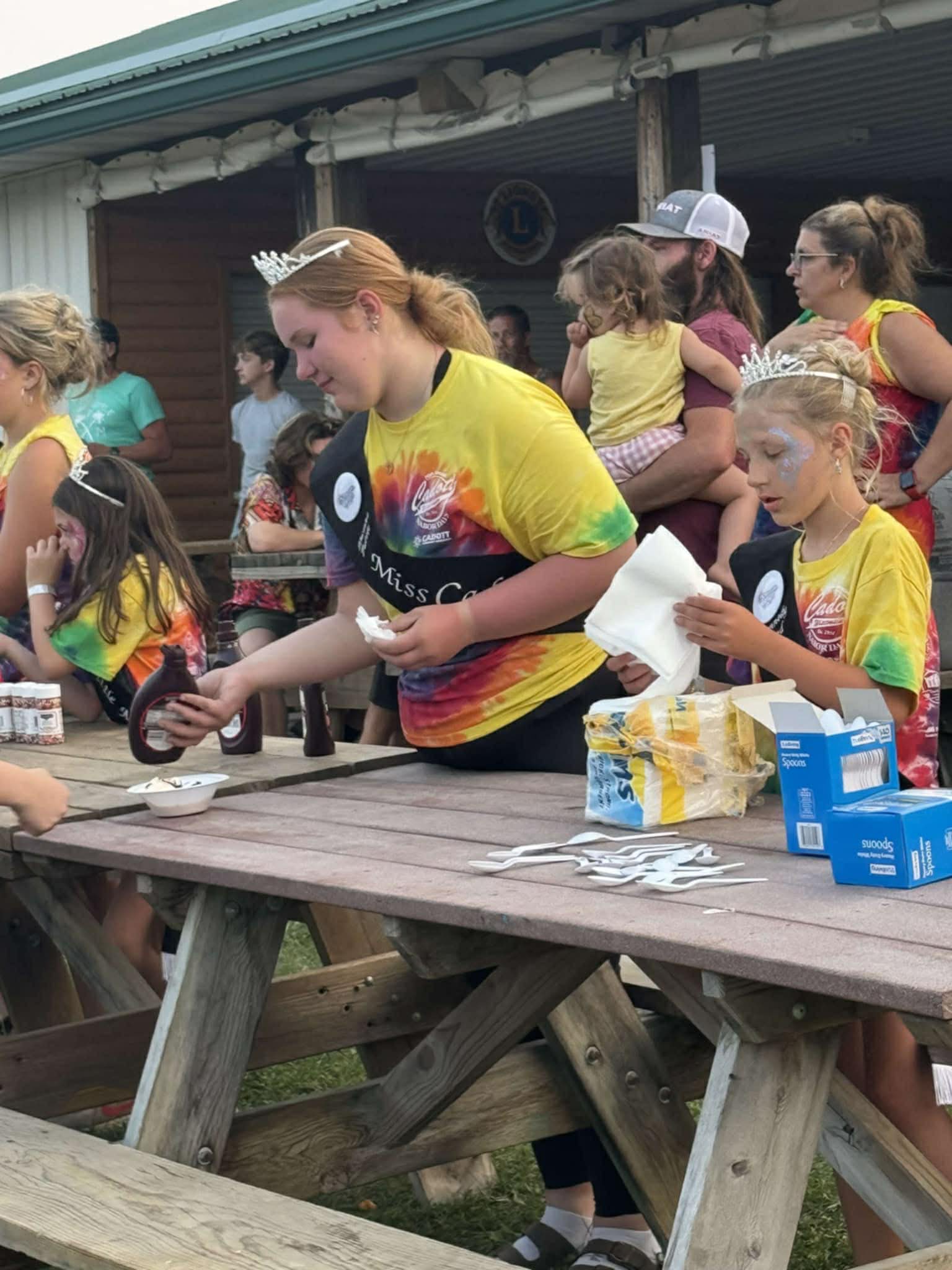 Royal court members serving root beer floats to kids